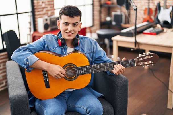 Young non binary man musician playing classical guitar at music studio - Photo, image