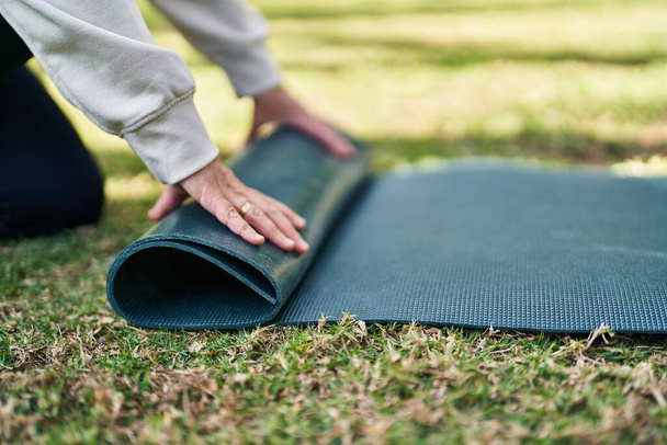 Middle age woman closing yoga mat at park - Fotoğraf, Görsel