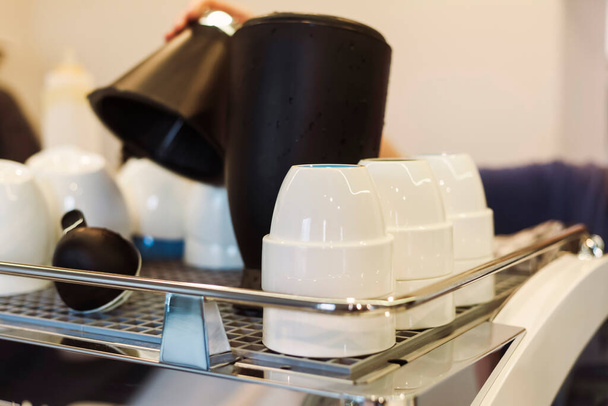 Tee- und Kaffeetassen heizen auf einer großen Kaffeemaschine im Café. - Foto, Bild