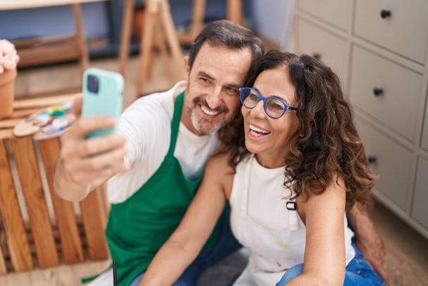 Muž a žena umělci dělat selfie podle smartphone kreslení v ateliéru umění - Fotografie, Obrázek