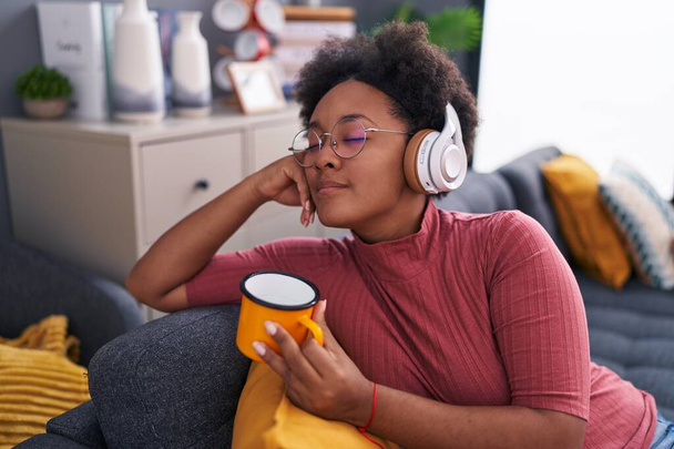 Африканська американка, яка слухає музику вдома, п "є каву. - Фото, зображення