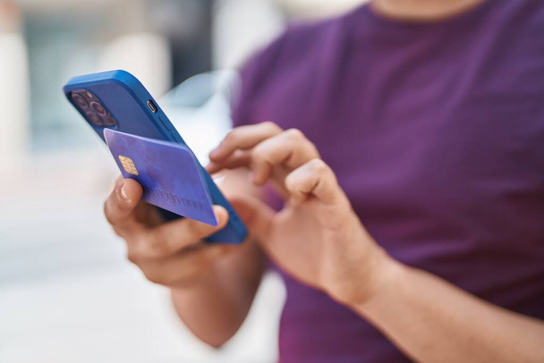 Jongeman met smartphone en creditcard op straat - Foto, afbeelding