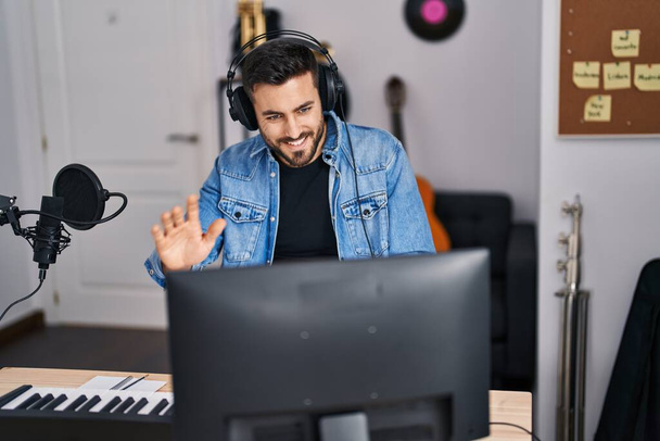 Young hispanic man artist smiling confident having video call at music studio - Photo, Image