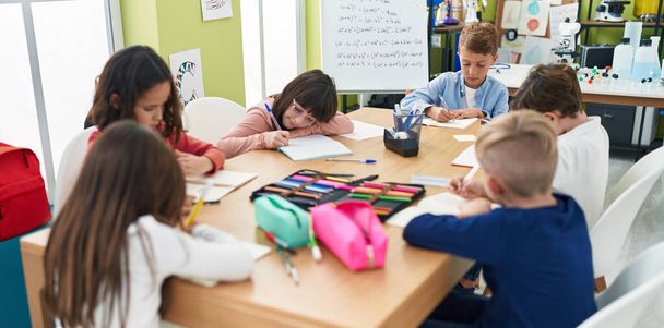 Gyerekek egy csoportja ül az asztalon és tanul az osztályteremben. - Fotó, kép