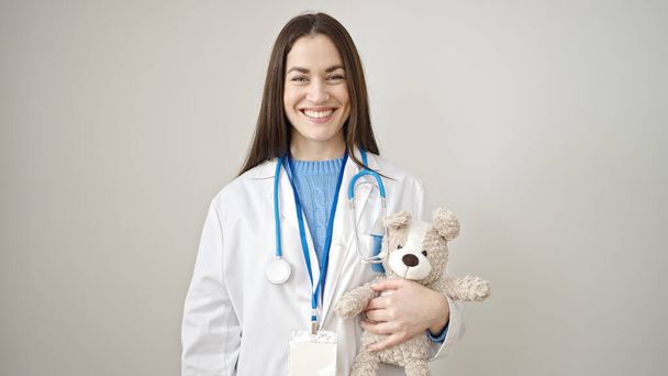 Young caucasian woman doctor smiling confident holding teddy bear over isolated white background - Foto, imagen