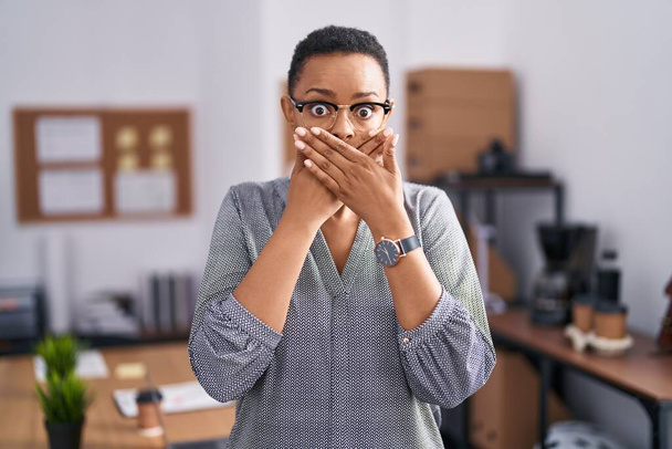 Afroameričanka pracující v kanceláři s brýlemi v šoku zakryla ústa rukama, aby se nespletla. tajný koncept.  - Fotografie, Obrázek
