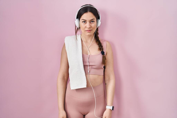 Young brunette woman wearing sportswear and headphones relaxed with serious expression on face. simple and natural looking at the camera.  - Fotoğraf, Görsel