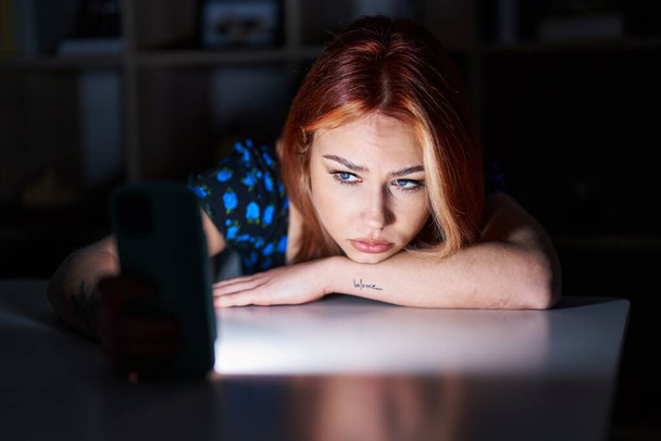 Young caucasian woman using smartphone with sadness expression at home - Foto, imagen