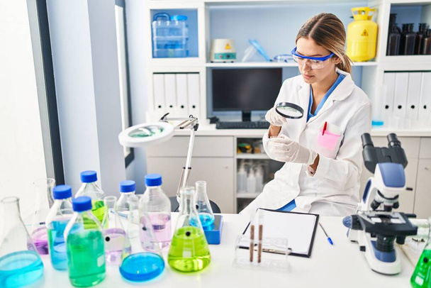 Young hispanic woman scientist looking sample using loupe at laboratory - Foto, Bild