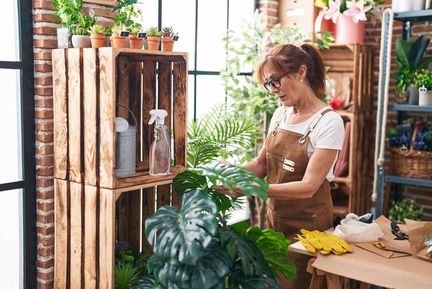 Mulher de meia-idade florista usando difusor trabalhando na loja de flores - Foto, Imagem