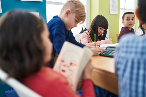 Группа детей, сидящих за столом, учится в классе - Фото, изображение