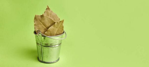 Sušené Bay listí v malém kovovém kbelíku na zeleném pozadí. - Fotografie, Obrázek