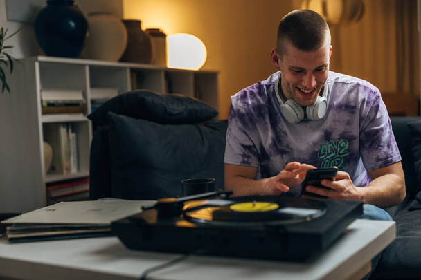 A happy handsome man is chatting with his friends while listening to music played on gramophone - Fotó, kép