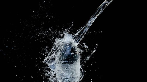 Abstract water jet crashes on a black background from a plastic bottle - 写真・画像