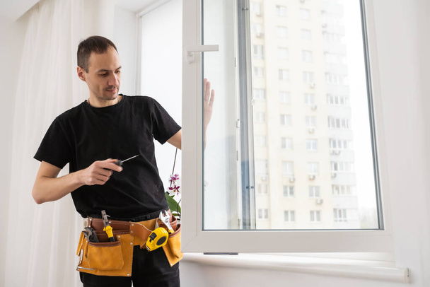 Handyman met een accuschroevendraaier om een raamgreep te installeren. Gekwalificeerde werknemers diensten, huis reparatie en renovatie. Hoge kwaliteit foto - Foto, afbeelding