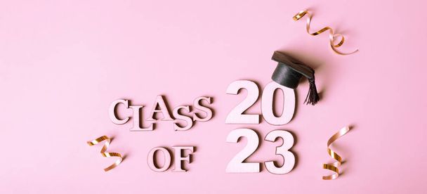Class of 2023 Konzept. Holzzahl 2023 mit abgestufter Kappe auf rosa Hintergrund. - Foto, Bild
