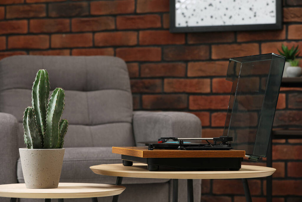 Stylish turntable with vinyl record, headphones and houseplant on table indoors - Foto, Bild