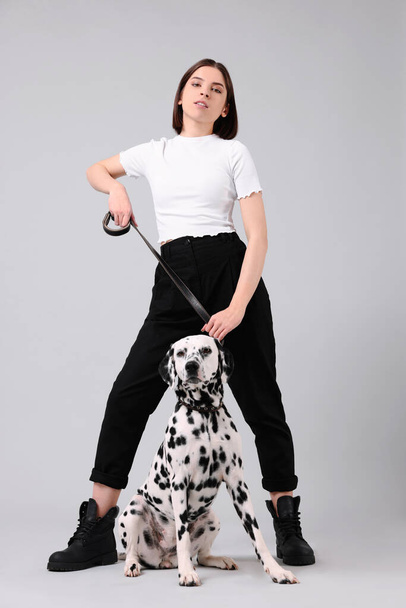 Beautiful young woman with her adorable Dalmatian dog on light grey background. Lovely pet - Foto, immagini
