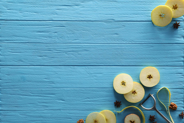 Food photography. Slices of apple, anise stars, walnuts and peeler on light blue wooden table, flat lay with space for text - Foto, Imagen