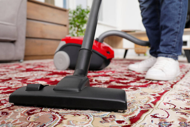 Man cleaning carpet with vacuum cleaner at home, closeup - Foto, immagini