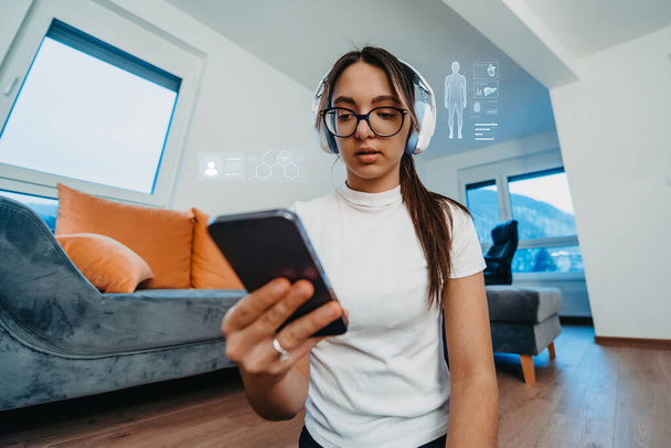 Sağlığını gösteren hologramlarla çevrili evde çeşitli egzersizler yaparken akıllı telefon kullanan bir kadın. Teknolojinin yakınsaması, ve ev bazlı egzersiz, önemini vurguluyor - Fotoğraf, Görsel