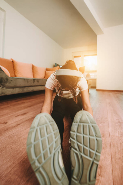 A woman stretching in her apartment during early morning after training , reflecting her dedication to a healthy lifestyle. This moment highlights the importance of regular exercise and self-care - Photo, Image