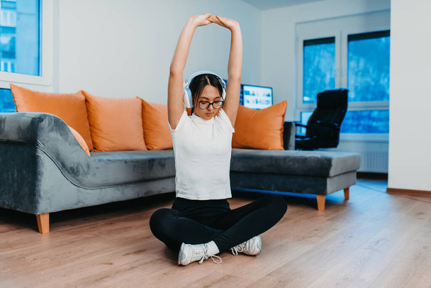 A woman stretching in her apartment during early morning after training , reflecting her dedication to a healthy lifestyle. This moment highlights the importance of regular exercise and self-care - Foto, imagen