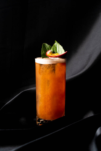 cocktail - infused tequila with basil, passion fruit and cinnamon, lime and mango in glass on dark background - Foto, imagen