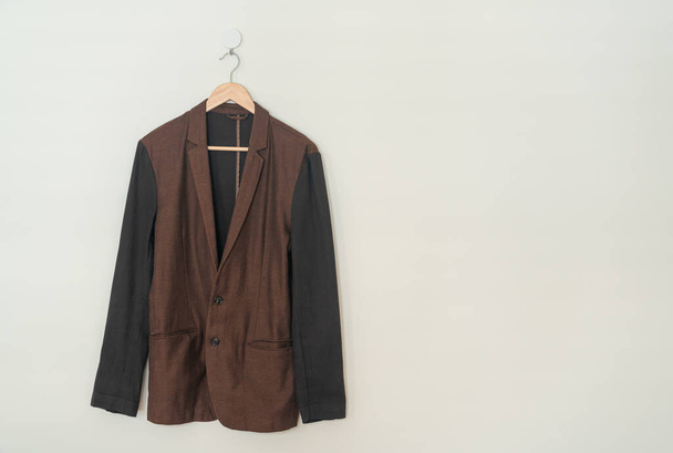 dark brown suit hanging with wood hanger on wall - 写真・画像