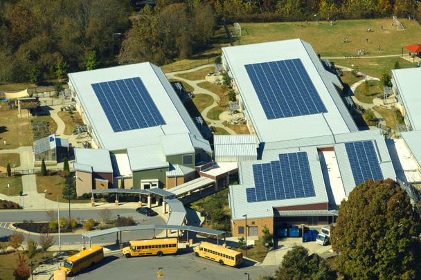 Katto amerikkalaisen koulun rakennuksen peitetty aurinkosähkö aurinkopaneelit sähköntuotantoon. Uusiutuvan energian käsite. - Valokuva, kuva