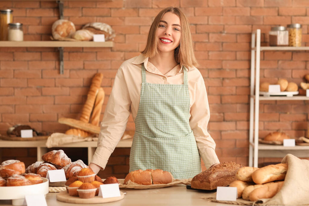 Naaras leipuri lähellä pöytää tuoreita leivonnaisia keittiössä - Valokuva, kuva