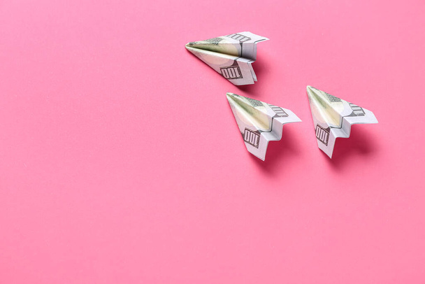 Origami samoloty wykonane z banknotów dolarowych na różowym tle - Zdjęcie, obraz