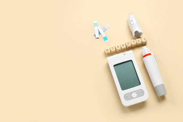 Word DIABETES with glucometer and lancet pen on beige background - Photo, Image