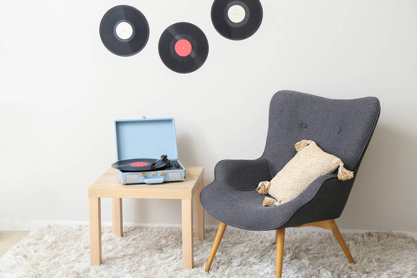 Record player με δίσκο βινυλίου στο τραπέζι και πολυθρόνα στο σαλόνι - Φωτογραφία, εικόνα