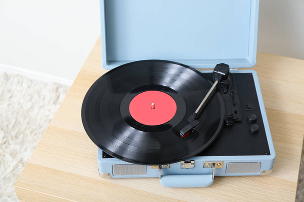 Lecteur de disques avec disque vinyle sur la table près du mur de lumière dans la chambre, gros plan - Photo, image