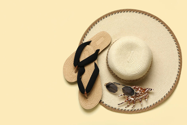 Slippers met zonnebril, schelp en hoed op beige ondergrond - Foto, afbeelding