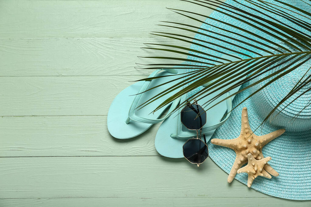 Flip-papucs napszemüveg, tengeri csillag, pálmalevél és kalap zöld fa háttér - Fotó, kép