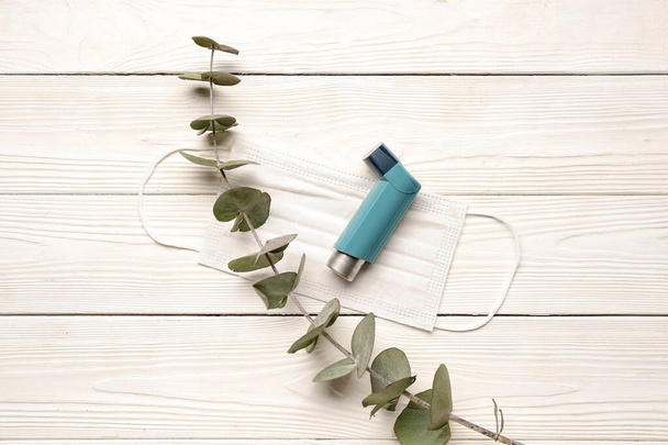 Astma inhalator met eucalyptus tak op witte houten ondergrond - Foto, afbeelding