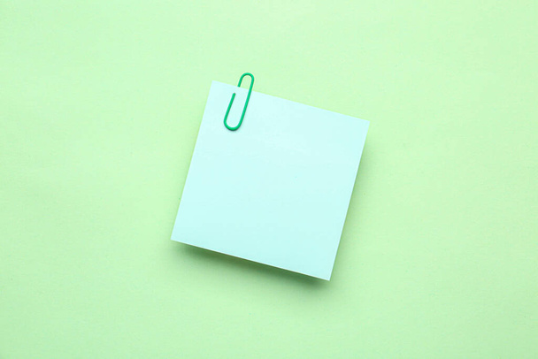 Sticky note with paper clip on green background - Photo, Image