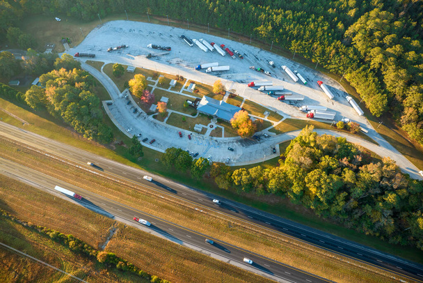 Top view of large rest area near busy multilane american freeway with fast moving cars and trucks. Recreational resting place during interstate traveling. - Zdjęcie, obraz
