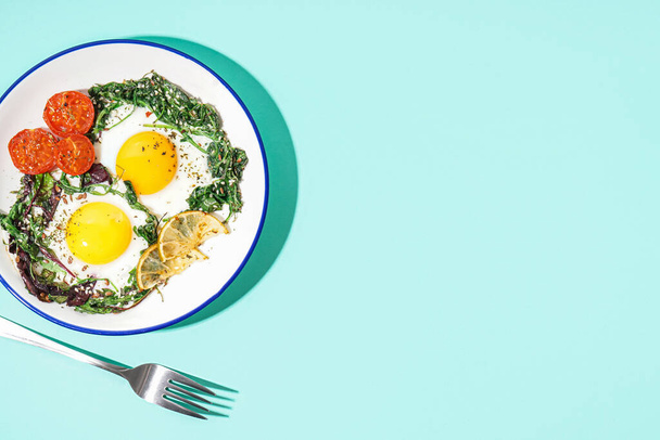 Plate with tasty fried eggs and salad on blue background - Φωτογραφία, εικόνα