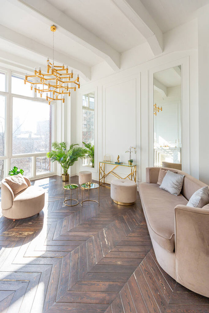 very light and bright interior of luxurious cozy living room with chic soft beige furniture with gold metallic elements, huge window to the floor and wooden parquet - Φωτογραφία, εικόνα