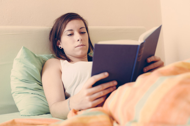 Young Woman Reading a Book on the Bed - Foto, Bild