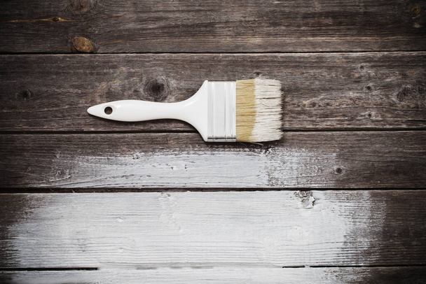 paintbrush with white paint on old wooden background - Fotó, kép