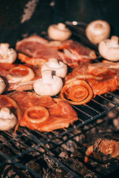 Свинина в томатном соусе с луковыми кольцами и грибами, готовящимися на открытом воздухе на гриле. барбекю на открытом воздухе - Фото, изображение