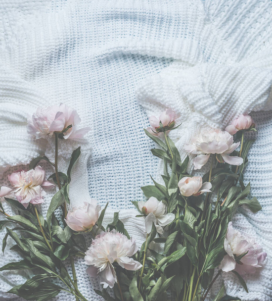 Background of pastel pink peonies scattered on a white knitted blanket. View from above. Beauty concept. Frame - Fotó, kép