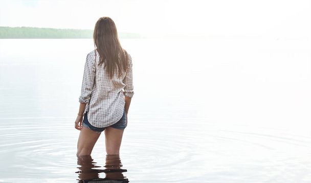 Nech svého ducha, ať se jemně pohupuje ve vodě. Zadní snímek mladé ženy stojící v jezeře - Fotografie, Obrázek