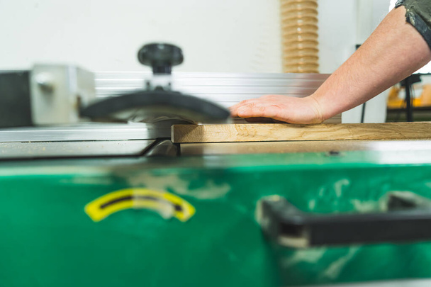 Крупним планом рука теслярів тримає дерев'яну дошку на професійній теслярській машині. Інструменти, що використовуються в деревообробці. Високоякісна фотографія
 - Фото, зображення