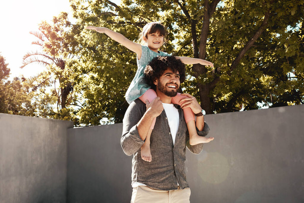 Papa maakt elke dag zo spannend. een vader geeft zijn dochtertje een ritje met de rug naar buiten - Foto, afbeelding