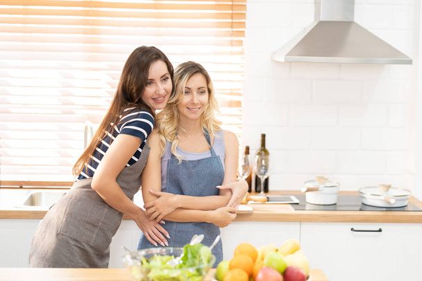 Happy LGBT lesbian couple dancing while cooking together at home. Girl dancing and turning, enjoying togetherness at background neon sign with word Together. Concept lgbt couple. - Foto, immagini
